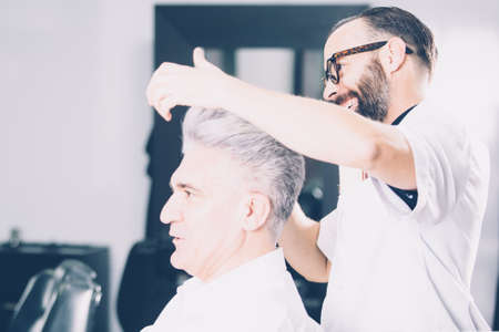 Horizontal indoors shot of cheerful barber working with client.の写真素材