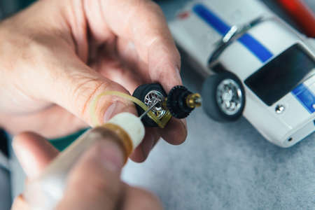 Hands of the person using oil for part of the small slot car.