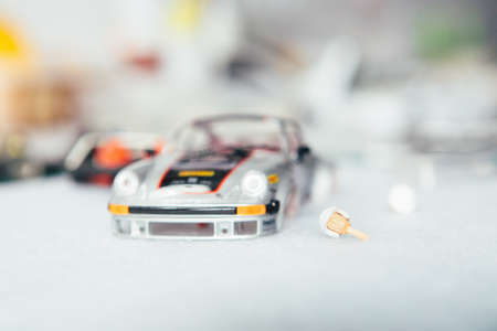 Slot car under construction and head of toy driver on a table in workshop.