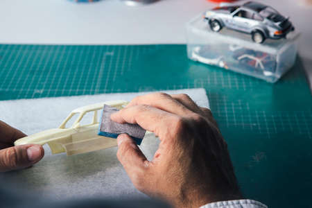 Close-up hands of person polishing miniature auto toy.の写真素材