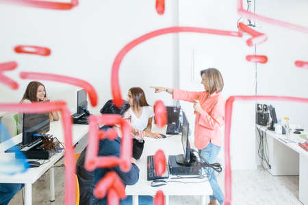 Side view of woman working with cheerful students in modern classroom having fun.