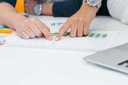 Hands of unrecognizable people pointing at paper during brainstorm in office.の写真素材