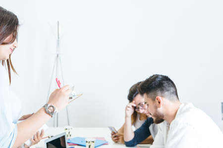 Side view of men and women in office sitting and coworking at table.の写真素材