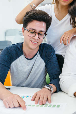 Smiling young man working and cooperating with colleagues in office.の写真素材