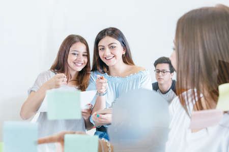 Two young girls pointing at stickers on wall discussing new plans and ideas.の写真素材