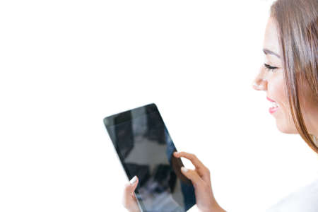 Side view of young cheerful woman holding tablet isolated on white background.の写真素材