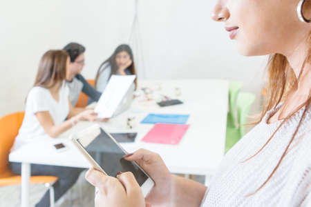Crop shot of woman holding tablet and posing on background of young coworkers at table with documents.の写真素材