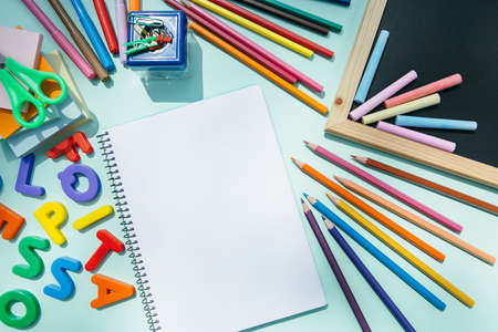 From above blank notepad and blackboard with colorful pencils and chalks.の写真素材