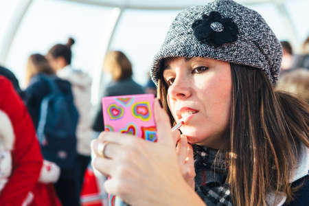 Young woman puts make up using a pencil and a small mirrorの写真素材