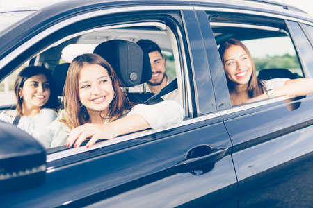 Young woman is driving a car with her friends on journeyの写真素材