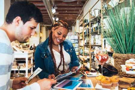 Young mixed race female and caucasian young male photographers co-working while eating a snackの写真素材