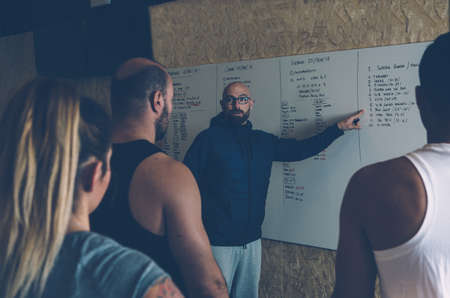 Male instructor is explaining the workout day at the box before a cross fit sessionの写真素材