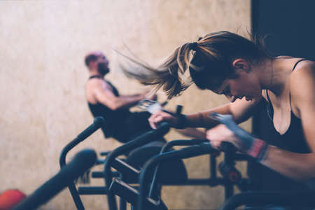 Side view of a sporty girl doing calorie assault exercise with her colleague doing glute ham developer routine on a fitness routine at the box gymの写真素材