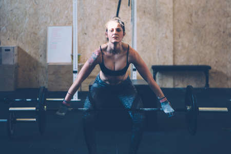 Young athlete woman doing hang power snatch with a barbell on a fitness routine at the box gymの写真素材