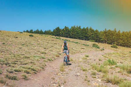Young sporty man is riding a bike in the mountain on a sunny day. Copy space area available