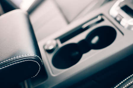 Cropped view of a front black leather handmade upholstered armrest of an elegant car. Top view