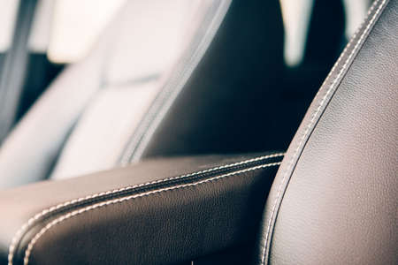 Detail of a stitch of an elegant car armrest upholstered in black handmade leather