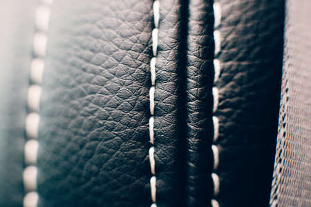 Close up of a detail of the stitches of a car seat upholstered in black handmade leather. Useful as a backgroundの写真素材