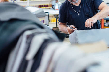 Cropped view of a man is working in the work table upholstering with leather a car seat in a...