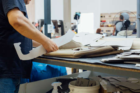 Cropped view of the hands of a man working on the seat upholstery of a car in a factoryの写真素材