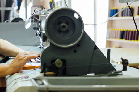 Cropped view of the hands of a woman working with the sewing machine to upholstering the interior car components in a upholstery factoryの写真素材