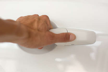 Close up of a male hand is opening a white car door holding the handleの写真素材
