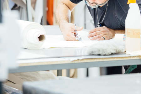 Cropped view of a male worker preparing the design of the leather in the work table to upholstering...