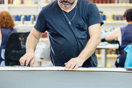 Cropped view of a male worker works in the design of the leather in the work table to upholstering...