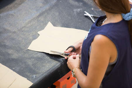 Cropped view of a top view of a woman cutting the leather pattern in the work table to upholstering...