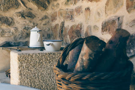 Detail of a roman wood burning oven with some antique objects and a basket full of wood.