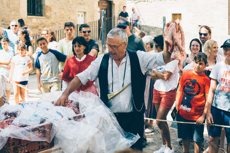 PUERTOMINGALVO, TERUEL, SPAIN - AUGUST 5, 2018: Middle aged man is making a pork meat auction in a medieval fair celebrated in Puertomingalvo, a small town located in the Maestrazgo Cultural Park in the region of Gudar Javalambre, in the province of Terueのeditorial素材