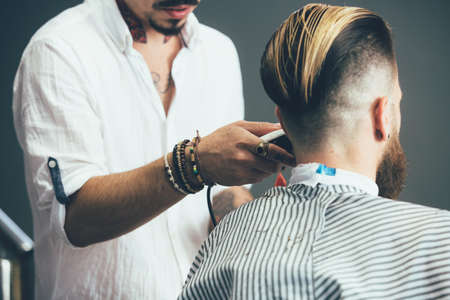 Cropped view of a trendy hairstylist working with the hair clipper getting the perfect shape of a customer beard at the barber shopの写真素材