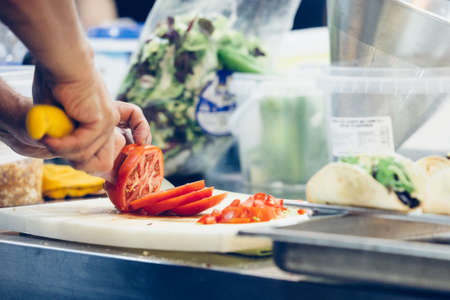 Cropped view of a chef is cutting slices of tomato ready to prepare the tasty typical spanish tapas