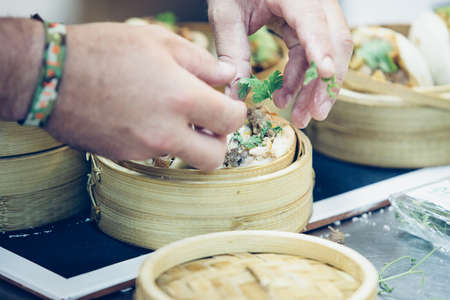 Detail of the hands of a chef adding chopped parsley in the tasty typical spanish tapas served in wooden basketsの写真素材