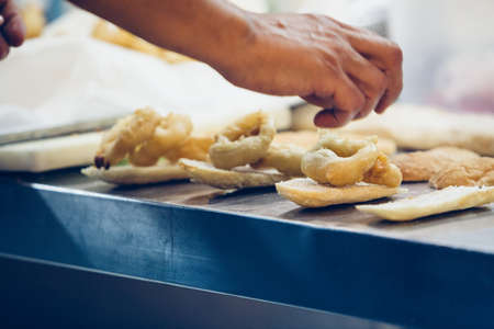 Detail of the hands of a chef is preparing the typical spanish tapas with fried squid rings on a...