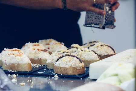 Detail of a tray full of russian salad with anchovy spanish tapas and a cropped view of the hands of...