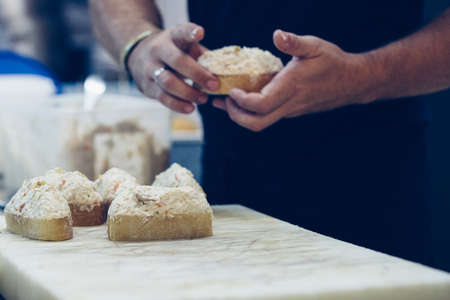 Hands of a chef is preparing the typical spanish tapas of russian salad on a crusty bread in a...