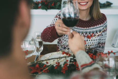 Cropped view of a smiling young woman is toasting on a Christmas time sitting on a decorated table with her beloved young manの写真素材
