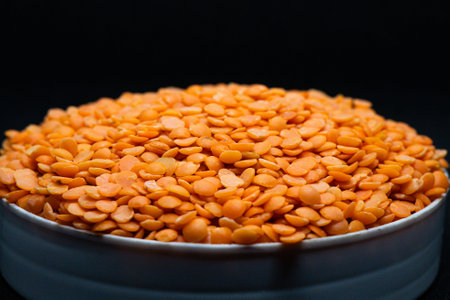 Red lentils in a bowl on a black background, close upの写真素材