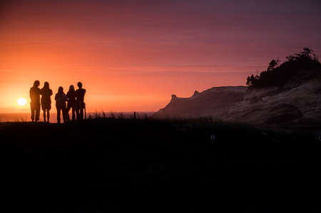 Friends in front of a sunset at Cape Kiwanda on the Oregon Coastの写真素材