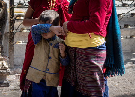 A boy child wiping his eyes with the sleeve of his traditional shirt.の写真素材