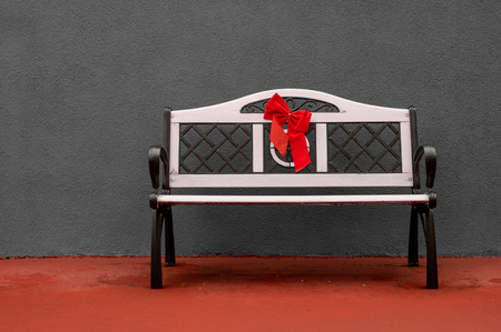 A bench sitting in front of a gray concrete wall.の写真素材