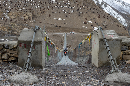 A motorcycle crossing over a cable stayed swinging footbridge.の写真素材