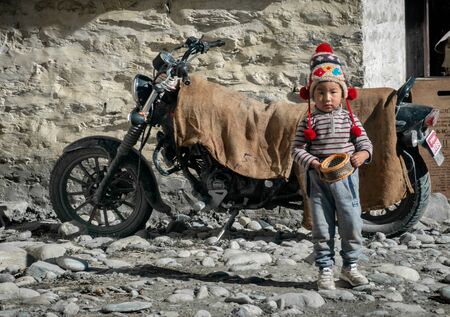 Mustang, Nepal - November 10, 2019: A young Nepali boy holding an air filter and  standing by the roadside in the Mustang region of Nepal.のeditorial素材