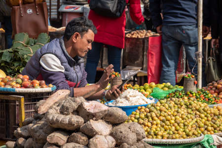 Kathmandu, Nepal - December 31, 2019: A man selling fruits and vegetables in a busy section of Kathmandu, Nepal.のeditorial素材