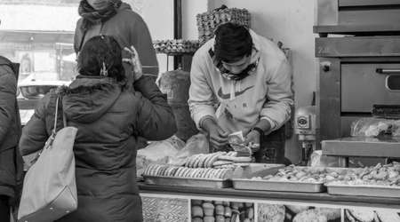 Kathmandu, Nepal - January 14, 2020: A Young Man Counting out Money for Change for a Customer at a Bakery Store in Kathmandu, Nepal.のeditorial素材