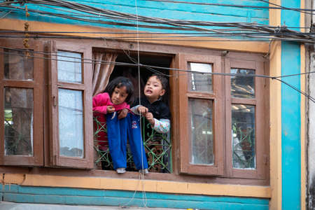 Kathmandu, Nepal - March 7, 2020: A Nepali boy and girl looking out of a window in Kathmandu City.のeditorial素材