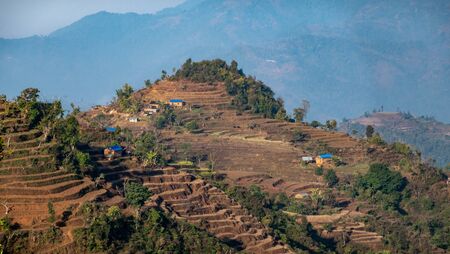 A few small village houses built on the hilltops of the Himalaya foothills of Nepal surrounded by...