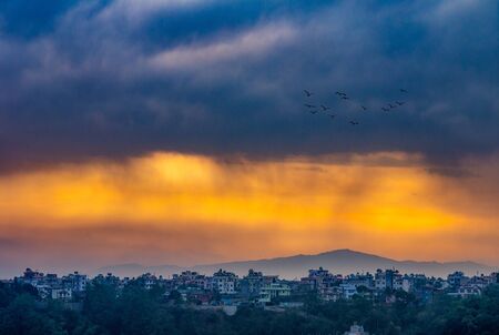 The eerie light of the morning sun shining through the storm clouds over the city of Kathmandu, Nepal.の写真素材