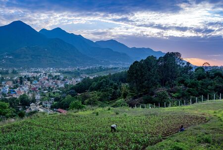 A Small Town in the Valley Surrounded By Mountains in the light of the setting sun with a man...